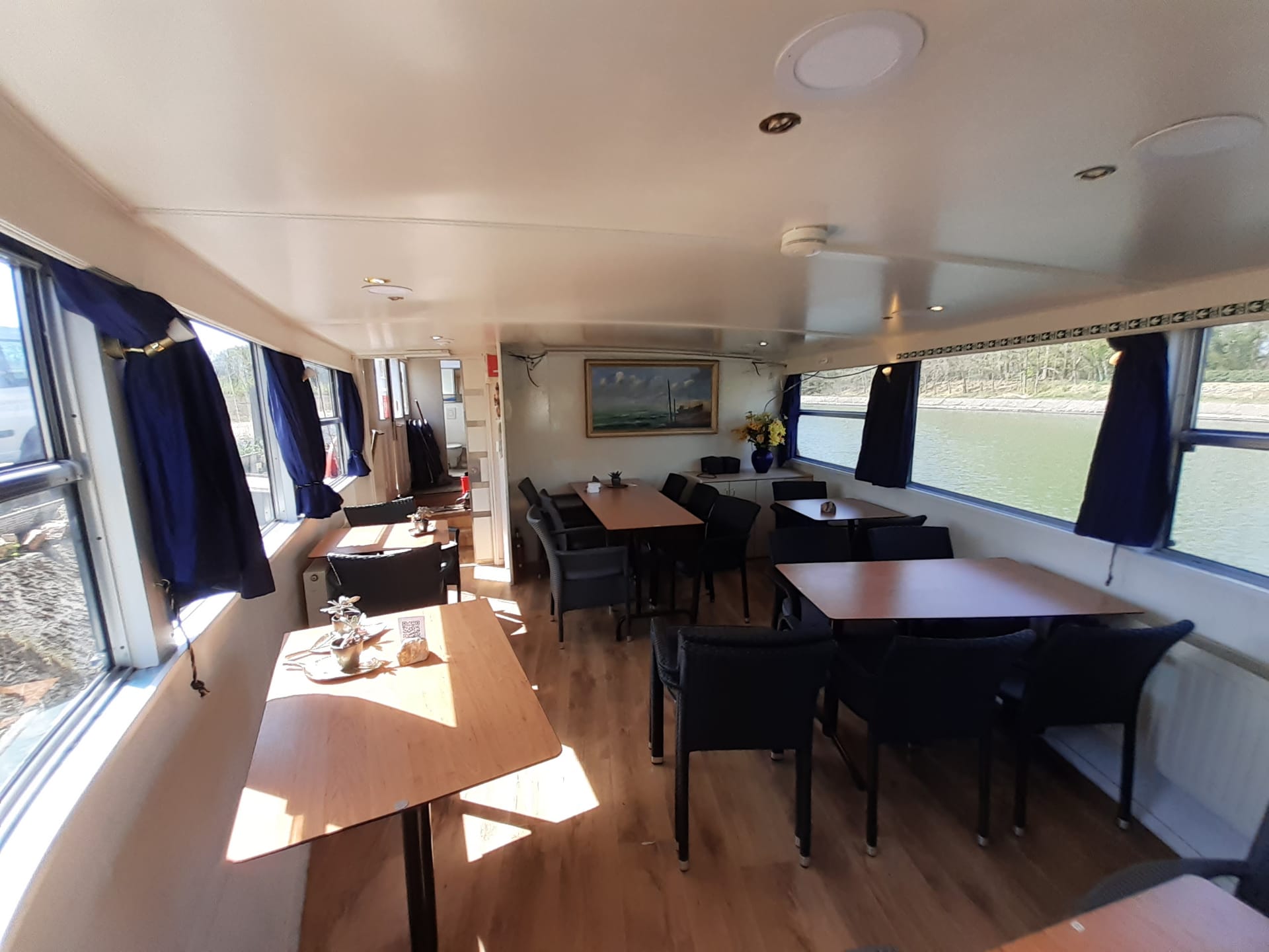 Loungeruimte met tafels en zicht op het kanaal